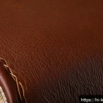 가죽공예 공예 작품 전시 - A close-up, high-resolution image of a premium leather jacket sleeve showcasing natural leather text...
